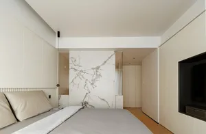 A modern minimalist bedroom with a marble accent wall.