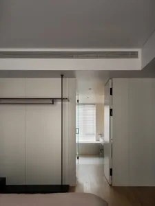 A minimalist bedroom with white walls, a wood floor, and simple furniture
