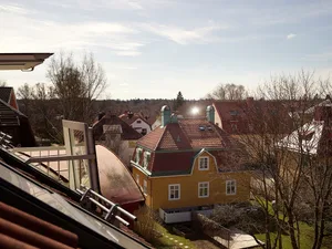 A bird's-eye view of residential houses with brick exteriors and tall trees in the background.