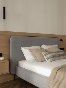 A minimalist bedroom with a fabric bed and soft furnishings