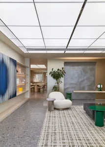 Modern lobby with concrete walls, white chairs, and green plants