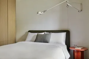 A minimalist bedroom featuring a white bed with a single decorative pillow.