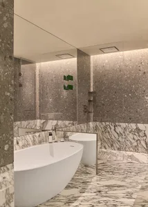 A modern bathroom featuring a freestanding bathtub and a sink against marble walls and floor.