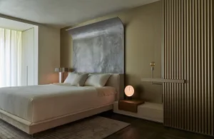 A modern bedroom with a metallic wall feature and a cozy bed setup.