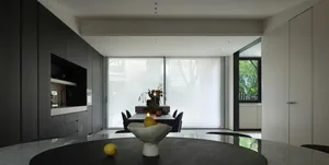 A modern dining room with black and white cabinets and countertops, metallic furnishings, and large windows with white sheer 