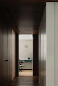 A modern interior hallway with wooden flooring and walls, featuring a view into a room with a wall mural depicting celestial 