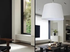 A modern living room with a minimalist white couch, a black coffee table, and large windows allowing natural light to flood t