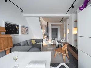 Modern living room with a sleek, grey sectional sofa adorned with soft yellow accents, set against a backdrop of minimalist w