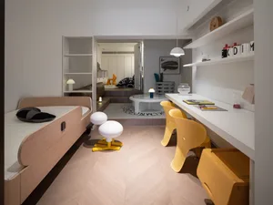 Minimalist bedroom with wood furniture, white walls, and a small study area with yellow chairs and a white desk.