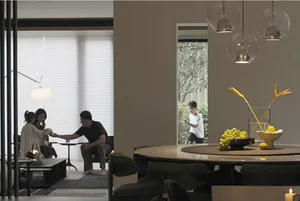 A modern residential dining room featuring a round dining table with a fruit bowl and a family of four interacting in the adj