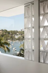 A view through glass windows overlooking a waterfront with boats and palm trees.