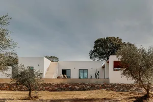 極簡住宅的白色混凝土外觀，搭配大面窗與石牆。
