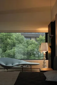 A modern bedroom featuring a glass window with a view of green trees outside.