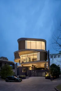 A modern concrete residential house at night illuminated with warm interior lights.