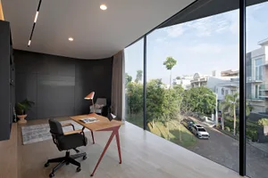 Modern home office with a glass wall overlooking a residential street