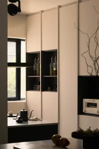 Modern kitchen featuring white and black shelves with various bottles and jars.