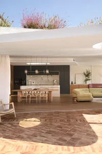 Modern living room and kitchen with open-concept layout, featuring wood flooring and furniture.