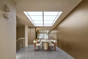 Contemporary dining room with modern minimalist style, featuring a rectangular table and white chairs under a skylight ceilin