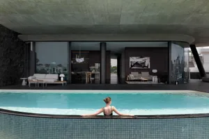 A modern residential space featuring a concrete interior design, with a person relaxing in a swimming pool.