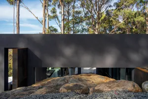 A minimalist residential house with concrete walls, surrounded by nature.