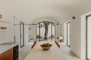 A minimalist residential dining room featuring concrete elements and a bowl of oranges on the table.