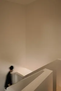 A minimalist interior design featuring a concrete staircase with a blurred human figure.