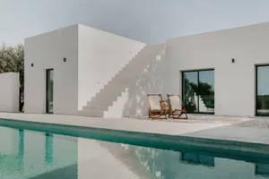 A modern white house with a concrete exterior and a pool.
