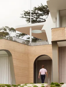 Modern residential entrance featuring a curved sandstone facade and architectural design.