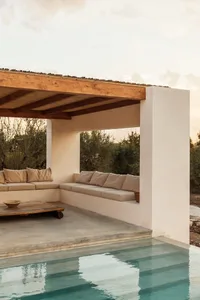 A minimalist outdoor patio featuring concrete seating and wooden canopy.
