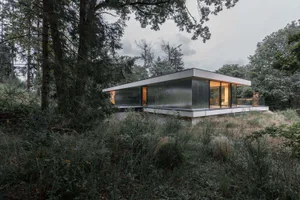 Modern residential exterior featuring metallic clad windows and a flat roof.