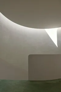 Modern interior design featuring curved concrete walls and dramatic light play.