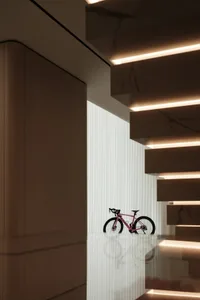 A minimalist interior design featuring a bike displayed below a modern marble staircase.
