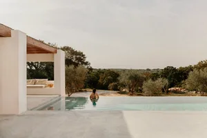 Person relaxing in a minimalist residential pool area surrounded by concrete.