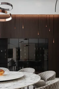 Modern dining room featuring a round marble table surrounded by upholstered chairs, with a wall of vertical wood panels and b