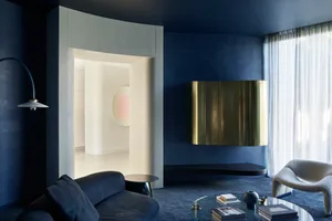 Modern living room with a metallic brass cabinet and navy blue walls.