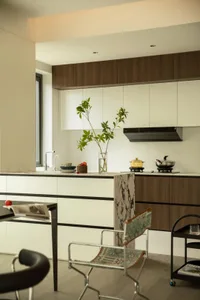 A modern kitchen with white marble countertops, wooden cabinets, and a black marble column.
