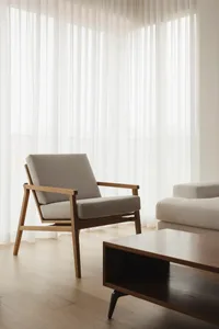 Modern living room featuring a cushioned chair with a wooden frame and light-colored fabric upholstery, alongside a wooden co