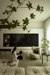 A modern living room with a marble accent wall, white furniture, and greenery.