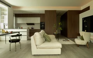 A sparse, minimalist living room with a white sofa, leather armchair, and marble elements.