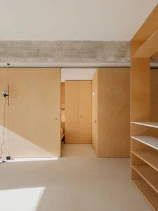 A minimalist room with wooden cabinets and concrete ceiling.