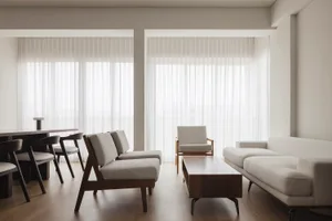 A modern, neutral-toned living room featuring a white sofa, a wooden coffee table, and white windows.