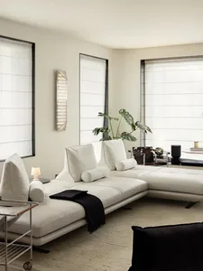 A modern white leather sofa in a living room with large windows and a minimalist design.