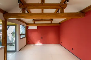 A minimalist empty room with red-painted walls and wooden beams.