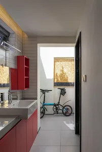 A minimalist bathroom featuring red cabinetry and a bicycle hanging on the wall.