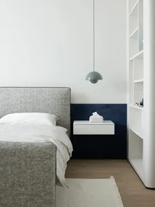A bedroom with a modern design featuring a fabric bed, wooden flooring, and metal accents.