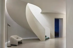 A modern living room with curved concrete walls and stairs.