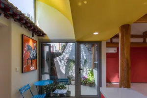 Modern interior space featuring a yellow ceiling, glass doors, and a seating area with chairs and potted plants.