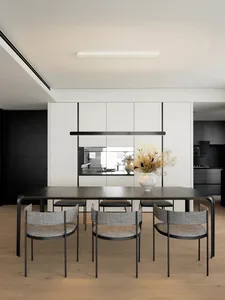 Modern minimalist dining room with metal table, wood flooring, and textured fabric chairs.
