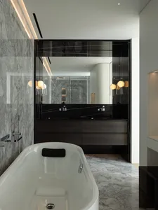 Modern bathroom interior featuring a freestanding bathtub, marble walls, and concrete accents.