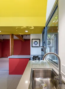 Modern kitchen featuring a red countertop and stainless steel sink.